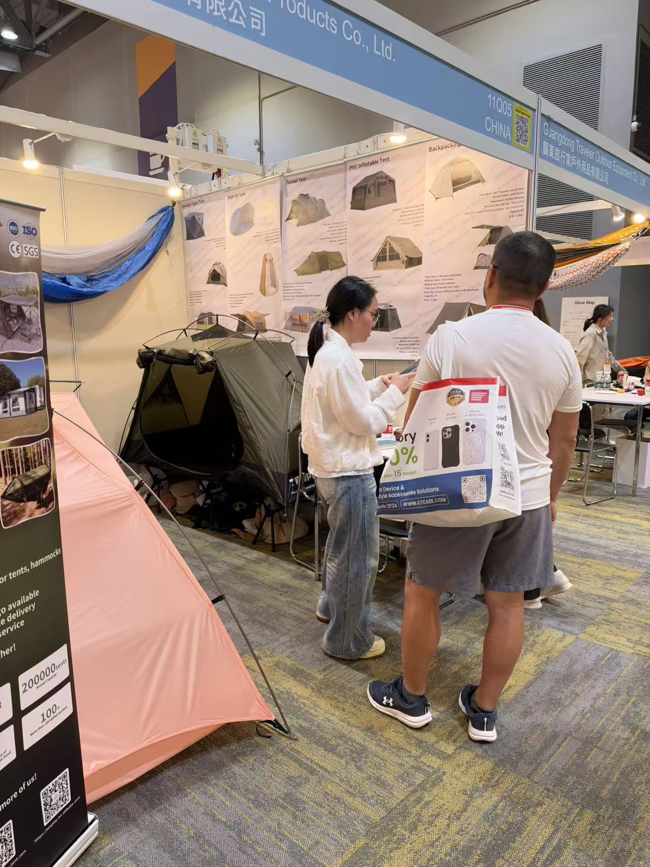 Tenplay team member and visitor consulting printed product information beside the tent display