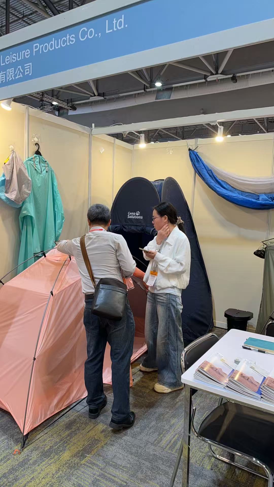 Tenplay team member speaking with visitors beside the pink tent display