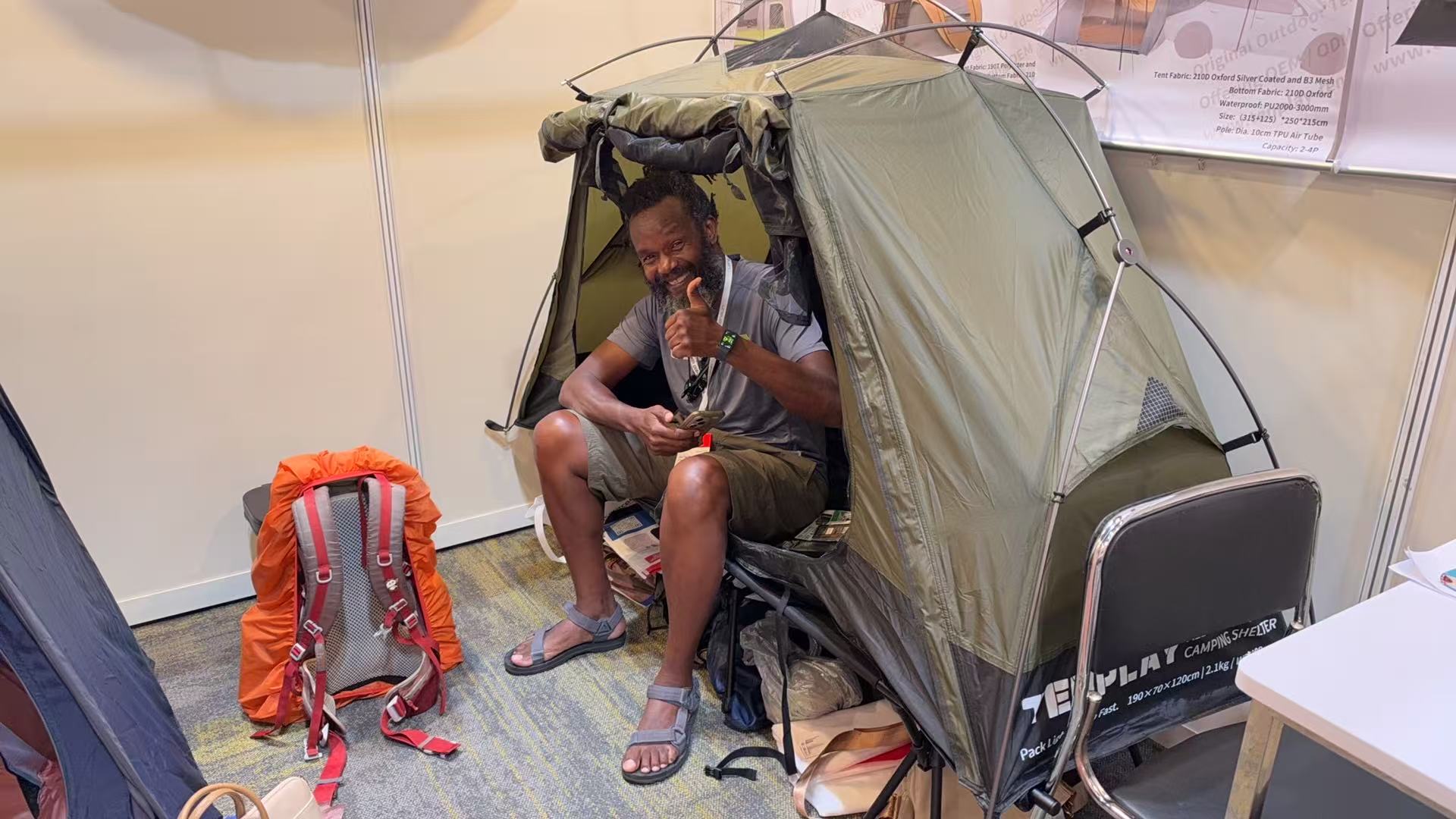 Visitor sitting inside an olive-green raised tent at the Tenplay exhibition booth